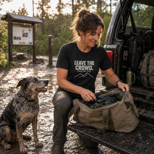 Woman in black t-shirt with text "LEAVE THE CROWD. Bring the Dog." packs bag next to dog.