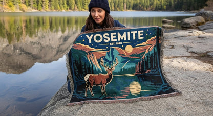 Woman holding a Yosemite-themed blanket by a lake