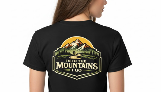 Black t-shirt with 'Into the Mountains I Go' design on the back, worn by a person.