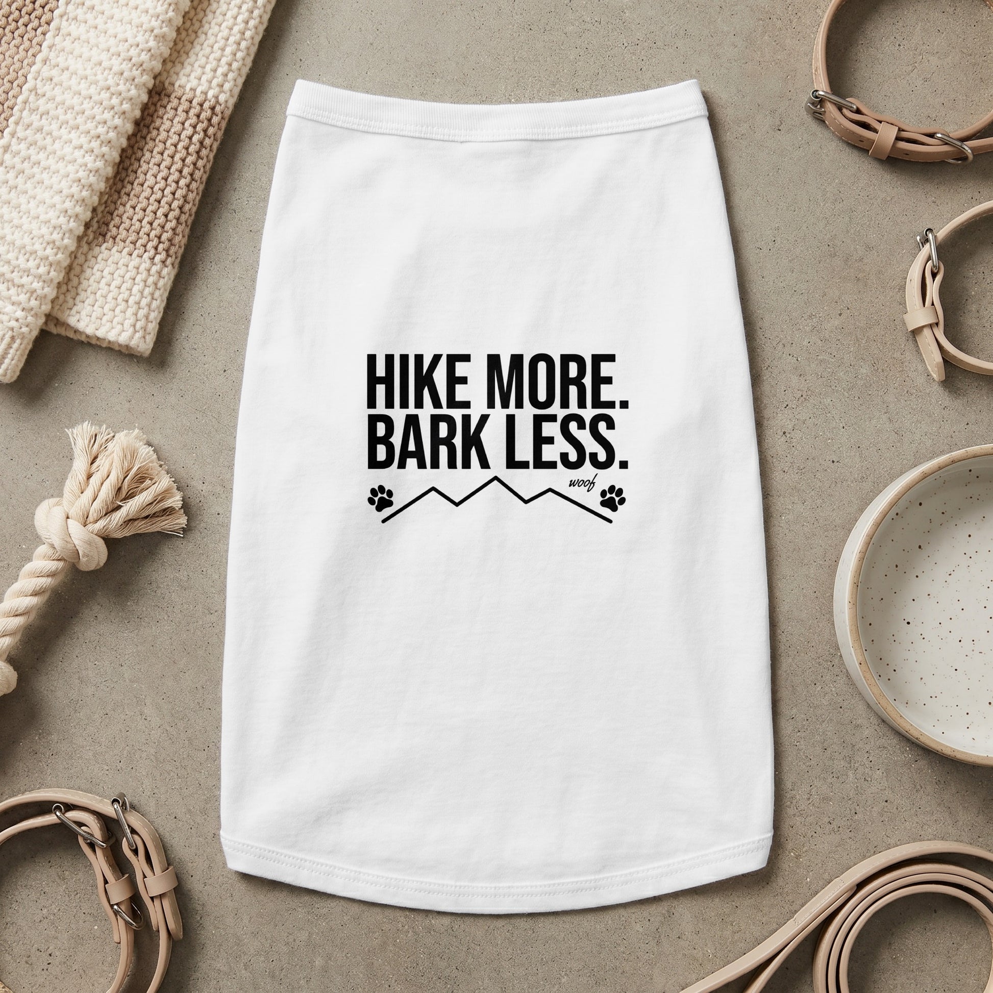 White dog shirt with black text "HIKE MORE. BARK LESS." and paw print mountain graphic.