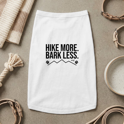 White dog shirt with black text "HIKE MORE. BARK LESS." and paw print mountain graphic.