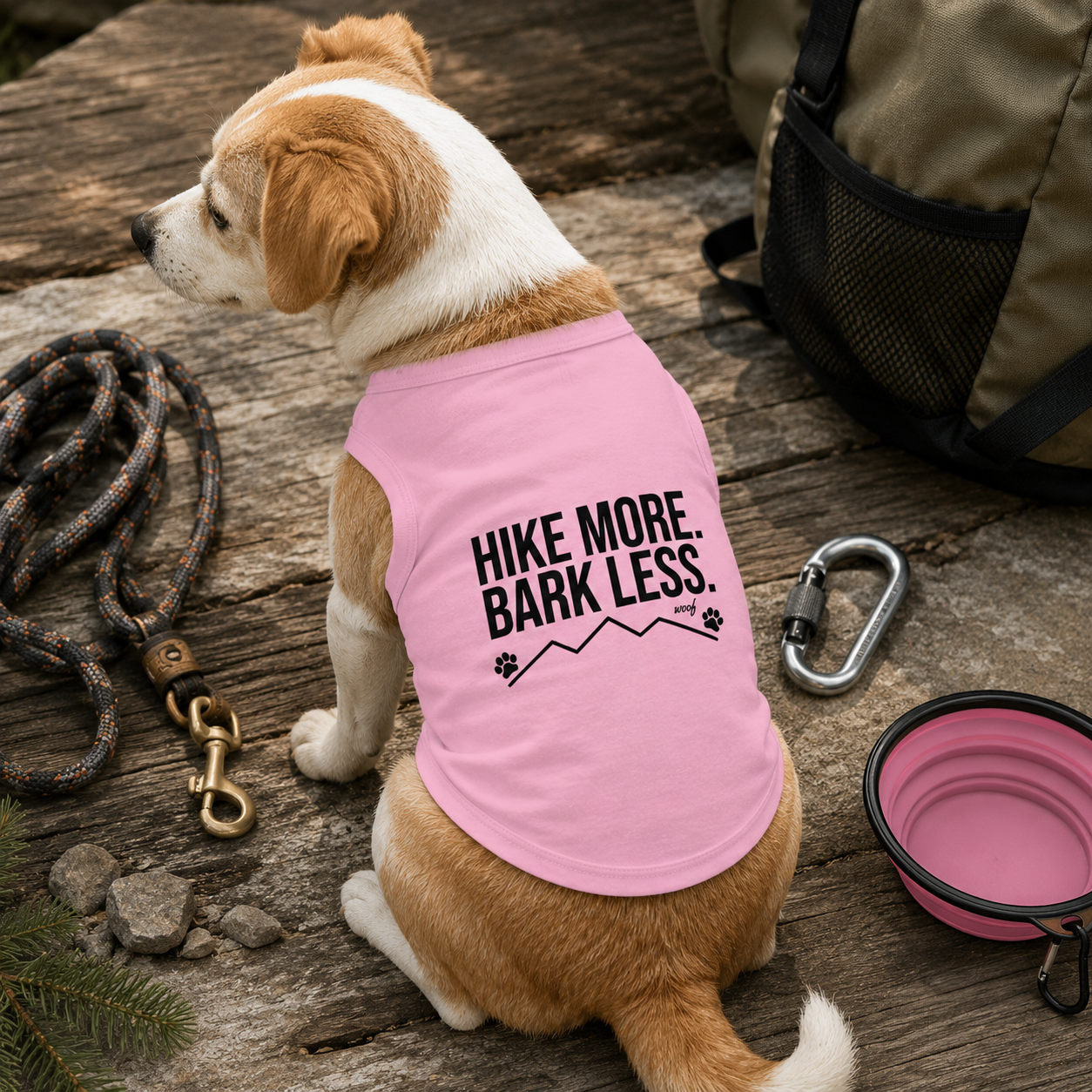 Dog wearing pink shirt with "Hike More. Bark Less." text and mountain graphic.