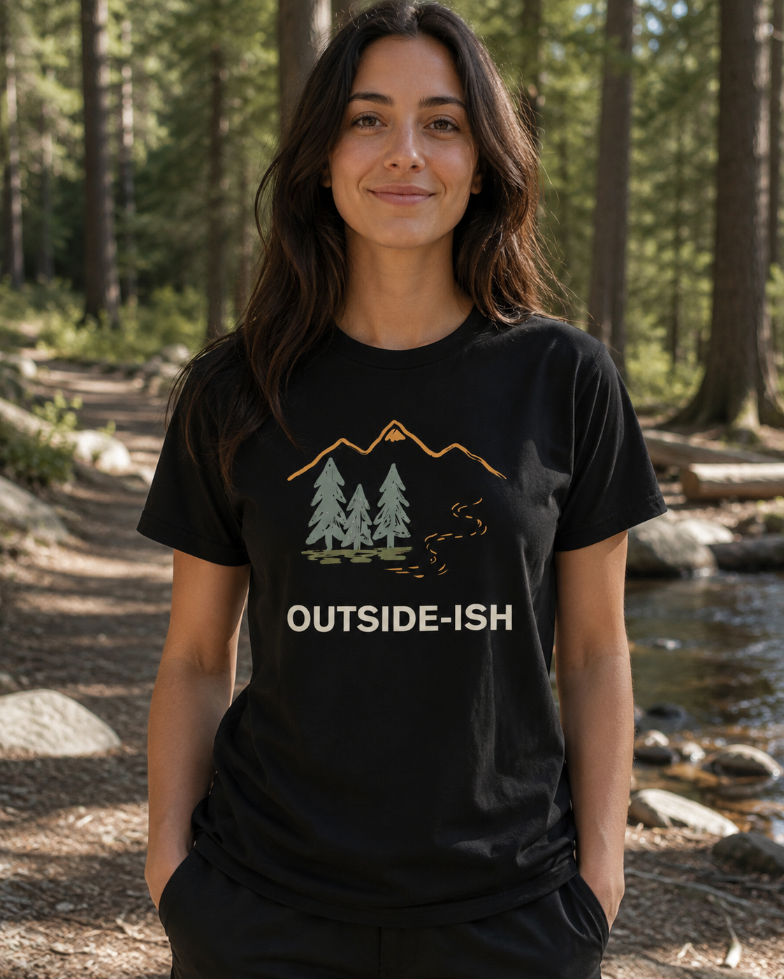 Woman wearing a black t-shirt with 'Outside-ish' design in a forest setting