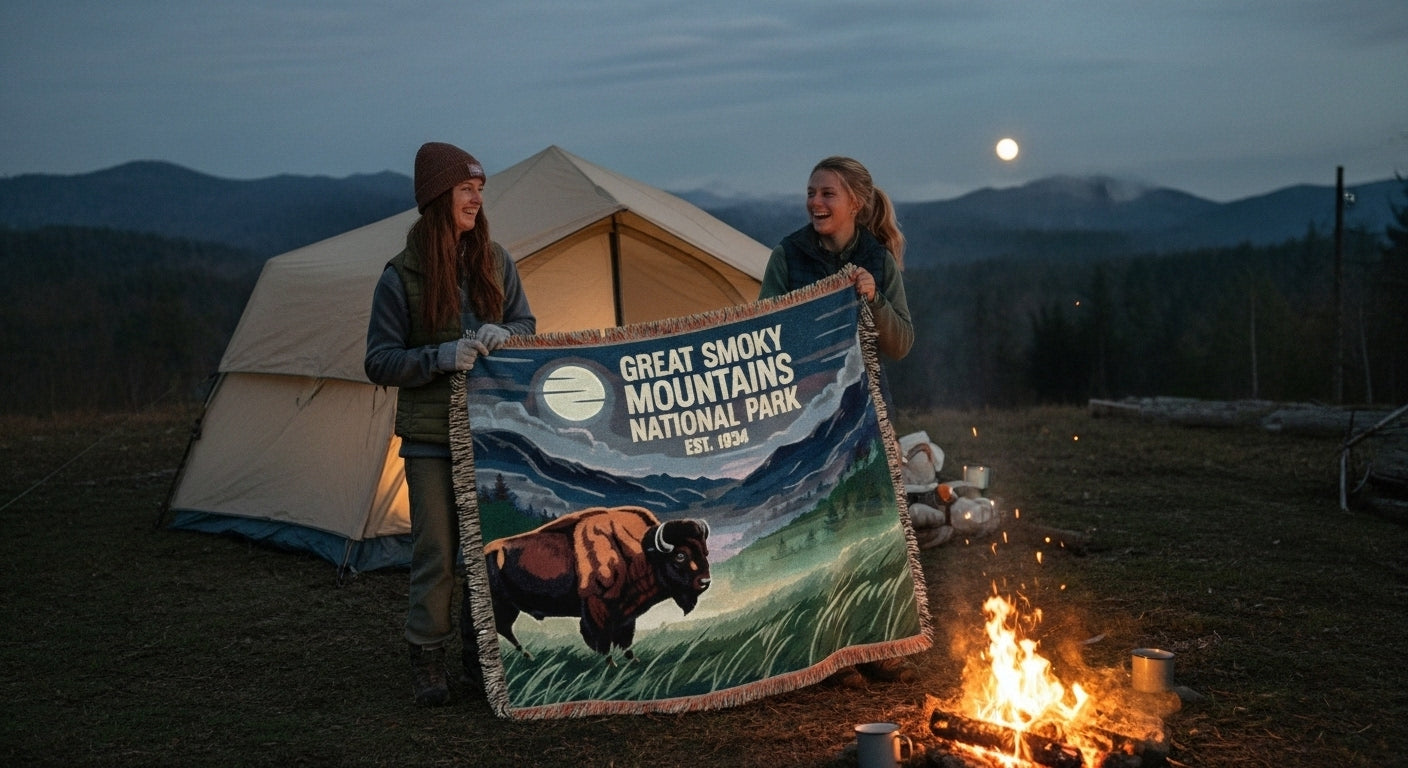 Two people holding a Great Smoky Mountains National Park blanket by a campfire at night.