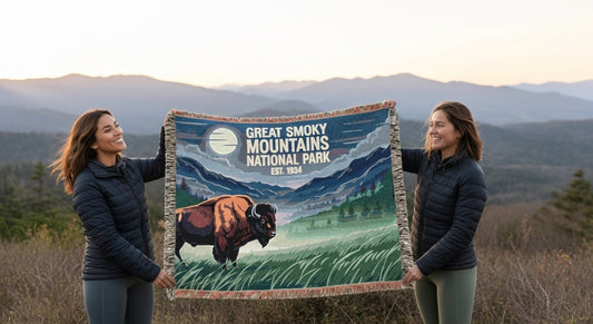 Two people holding a Great Smoky Mountains National Park blanket with a scenic design.