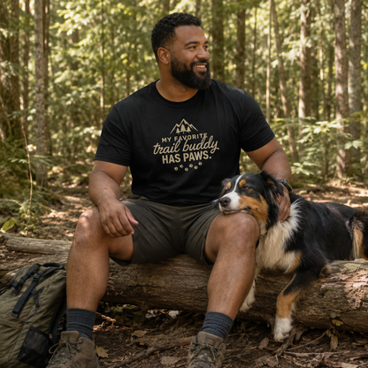 Man in black t-shirt with "my favorite trail buddy has paws" text sitting with dog.