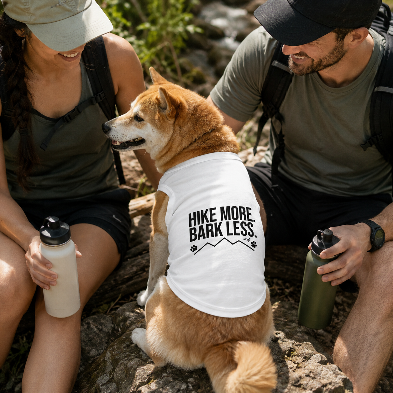 Shiba Inu dog wears white tank top with "Hike More Bark Less" text and paw prints.
